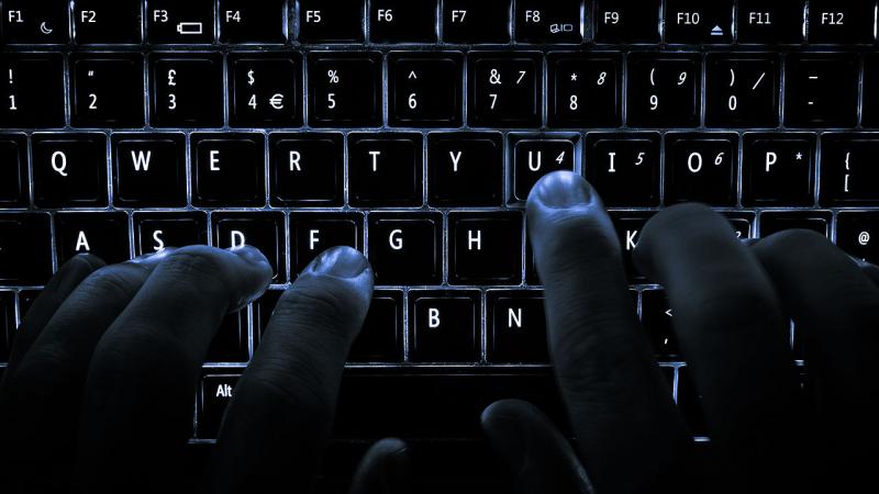Dark hands on a backlit keyboard