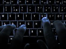 Dark hands on a backlit keyboard